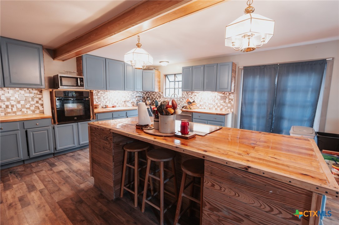 200 Williams Street Cuero, TX 77954 - Photo 6 of 17 a kitchen with stainless steel appliances kitchen island granite countertop a refrigerator a sink dishwasher a stove with wooden cabinets and floor