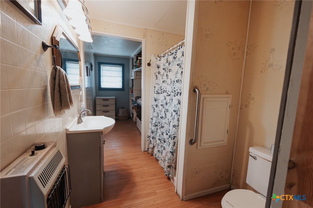 200 Williams Street Cuero, TX 77954 - Photo 7 of 17 a bathroom with a sink a toilet and shower curtain