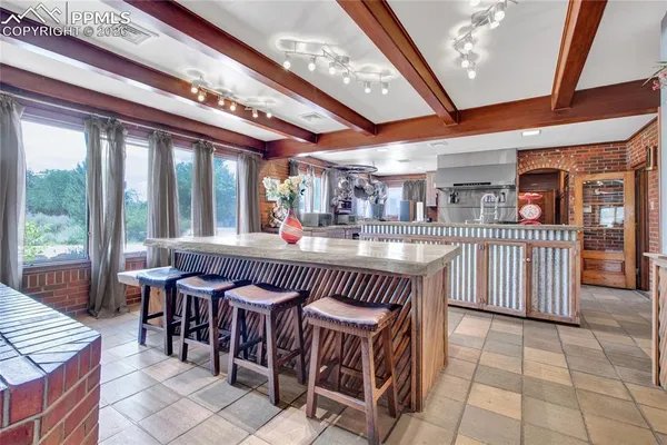 a dining hall with stainless steel appliances kitchen island granite countertop a table chairs and a large window