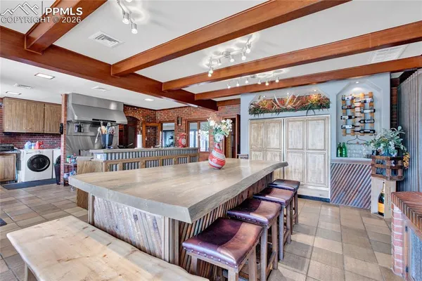 a dining hall with stainless steel appliances kitchen island granite countertop a table chairs and a wooden floor