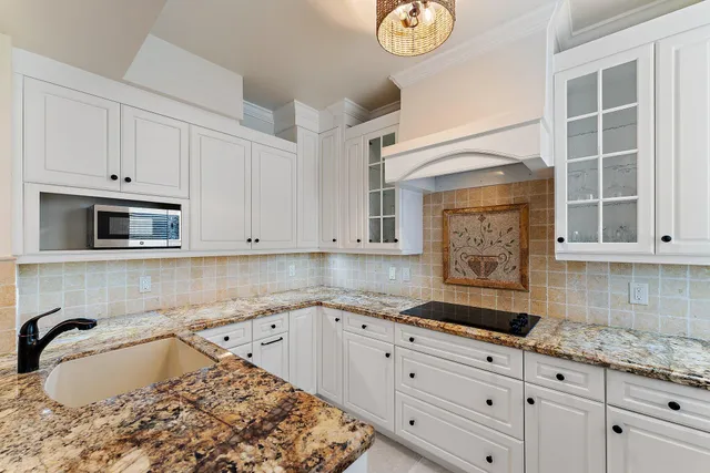 a kitchen with granite countertop white cabinets and a stove
