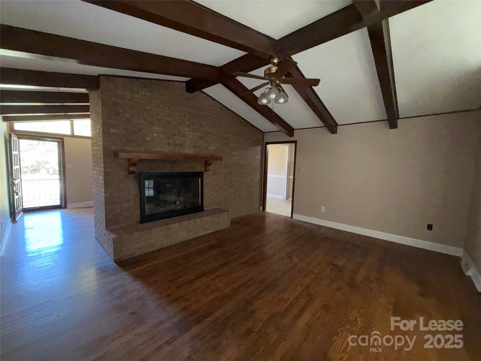 925 Perth Road Troutman, NC 28166 - Photo 7 of 31 an empty room with wooden floor fireplace and windows