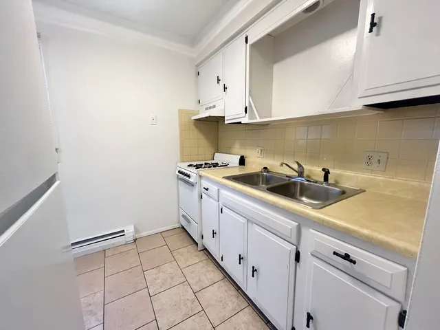 a kitchen with granite countertop white cabinets and white appliances