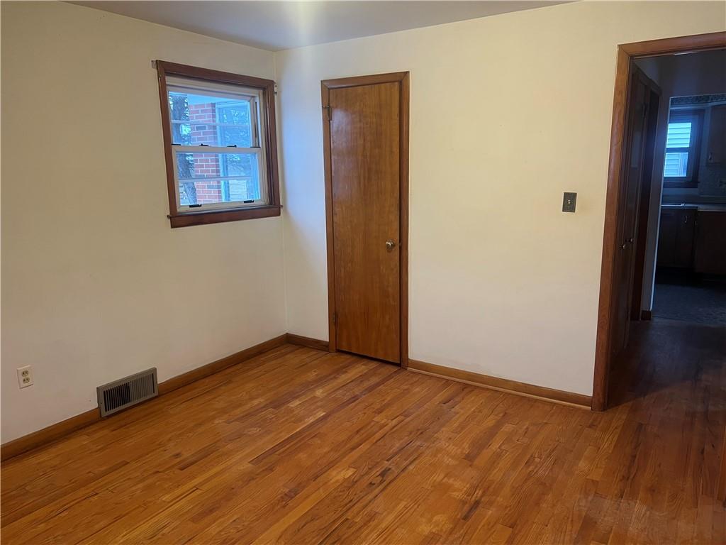 1020 Poe Street Vandergrift, PA 15690 - Photo 5 of 16 an empty room with wooden floor and windows