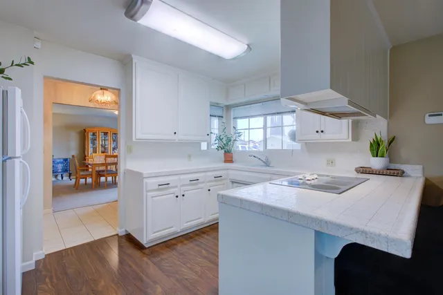 a kitchen with granite countertop a sink a stove cabinets and wooden floor