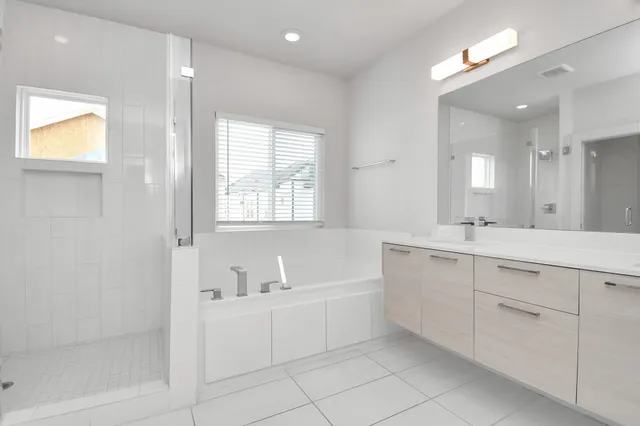 a spacious bathroom with a double vanity sink a mirror and a bathtub