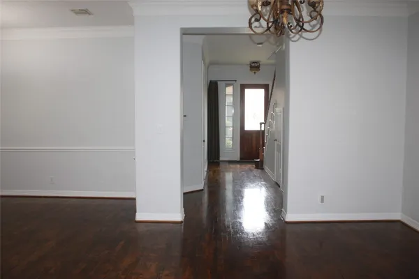 a view of a hallway with wooden floor and a chandelier