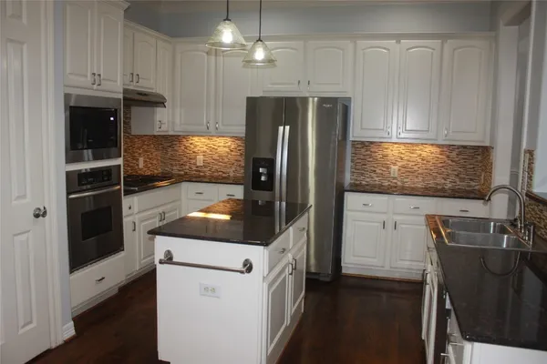 a kitchen with granite countertop a refrigerator stove and sink