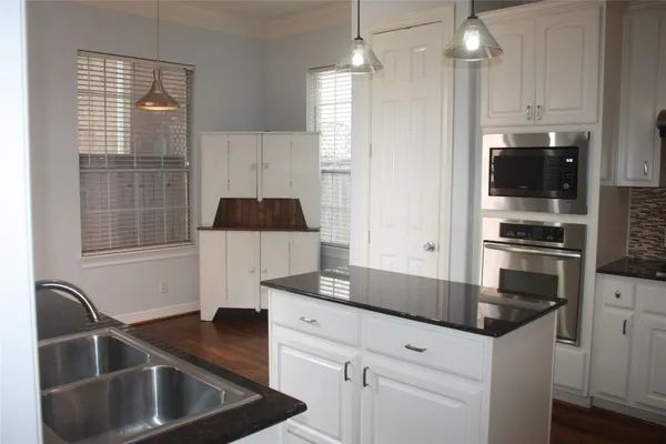 a kitchen with granite countertop a sink a stove and refrigerator