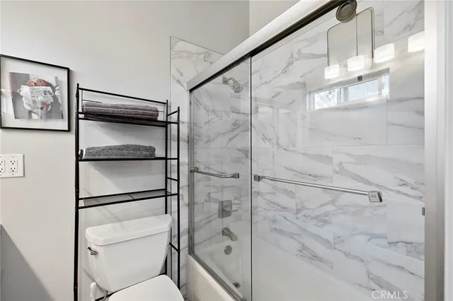 a bathroom with a toilet sink vanity granite and shower