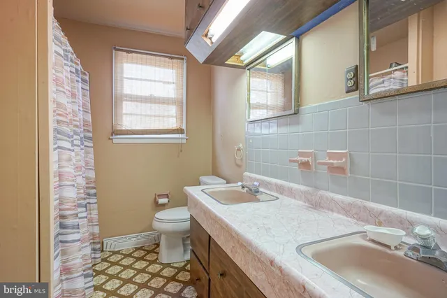 a bathroom with a granite countertop sink a toilet and shower