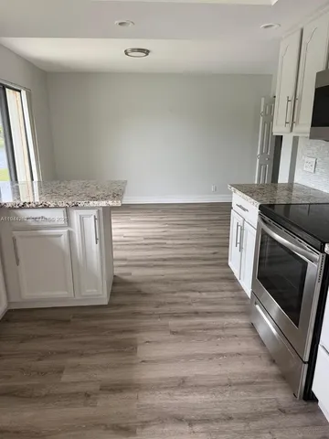 a kitchen with stainless steel appliances wooden floor a stove and a microwave