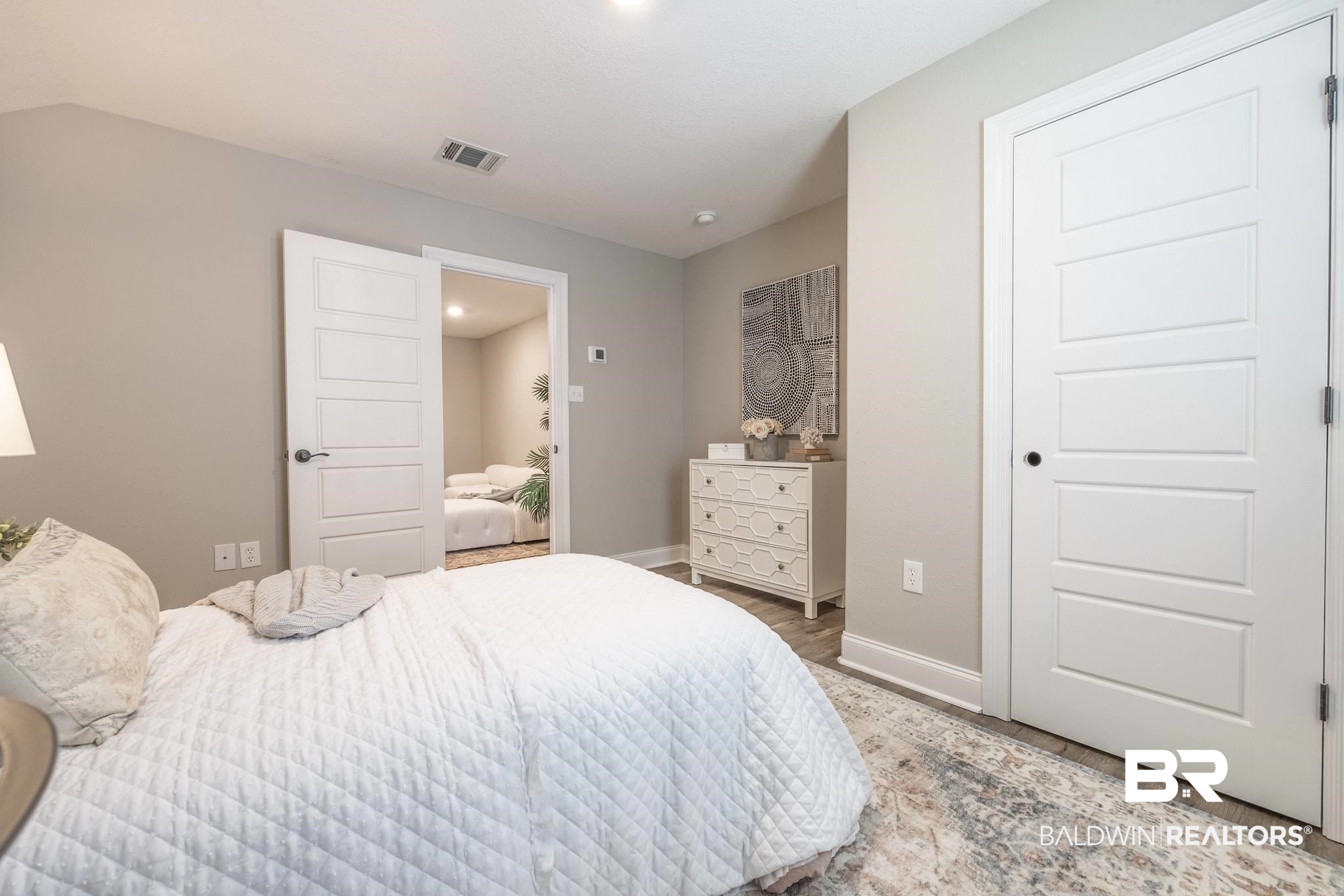 12918 Flanagan Street Elberta, AL 36530 - Photo 6 of 33 Bedroom featuring light gray wall paint, wood-finish flooring, white baseboards, and a white paneled door with black hardware