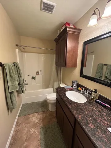 a bathroom with a granite countertop sink mirror vanity and toilet