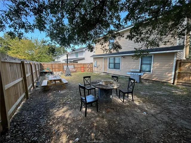 a backyard of a house with barbeque oven table and chairs