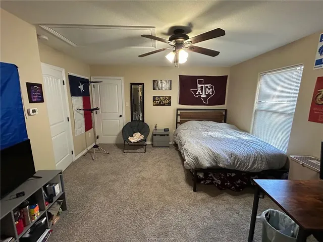 a spacious bedroom with a bed and a flat tv screen on the wall