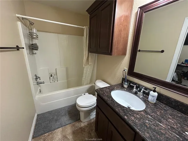 a bathroom with a granite countertop sink toilet and shower