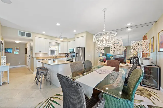 a view of a dining room and livingroom furniture a rug a chandelier and kitchen view