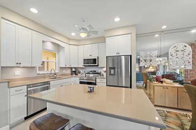 a kitchen with stainless steel appliances granite countertop a refrigerator a stove a sink a oven and white cabinets with wooden floor