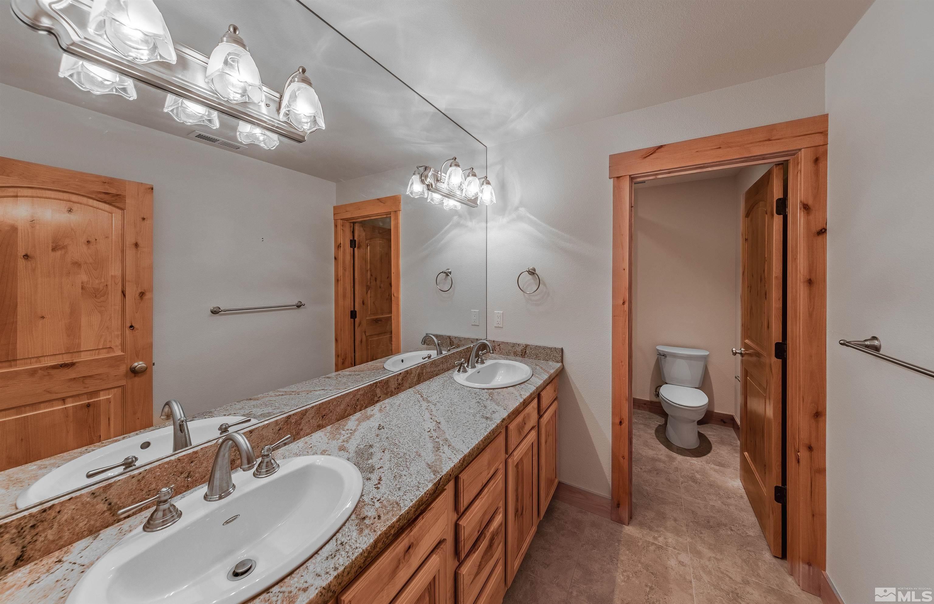 278 Andria Drive Stateline, NV 89449 - Photo 21 of 37 a bathroom with a granite countertop sink a toilet and a large mirror