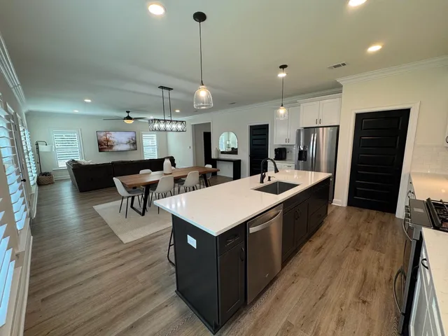 a large kitchen with a center island wooden floor and stainless steel appliances