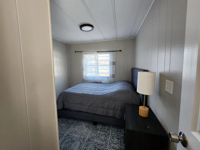 a bedroom with a bed and a lamp on desk