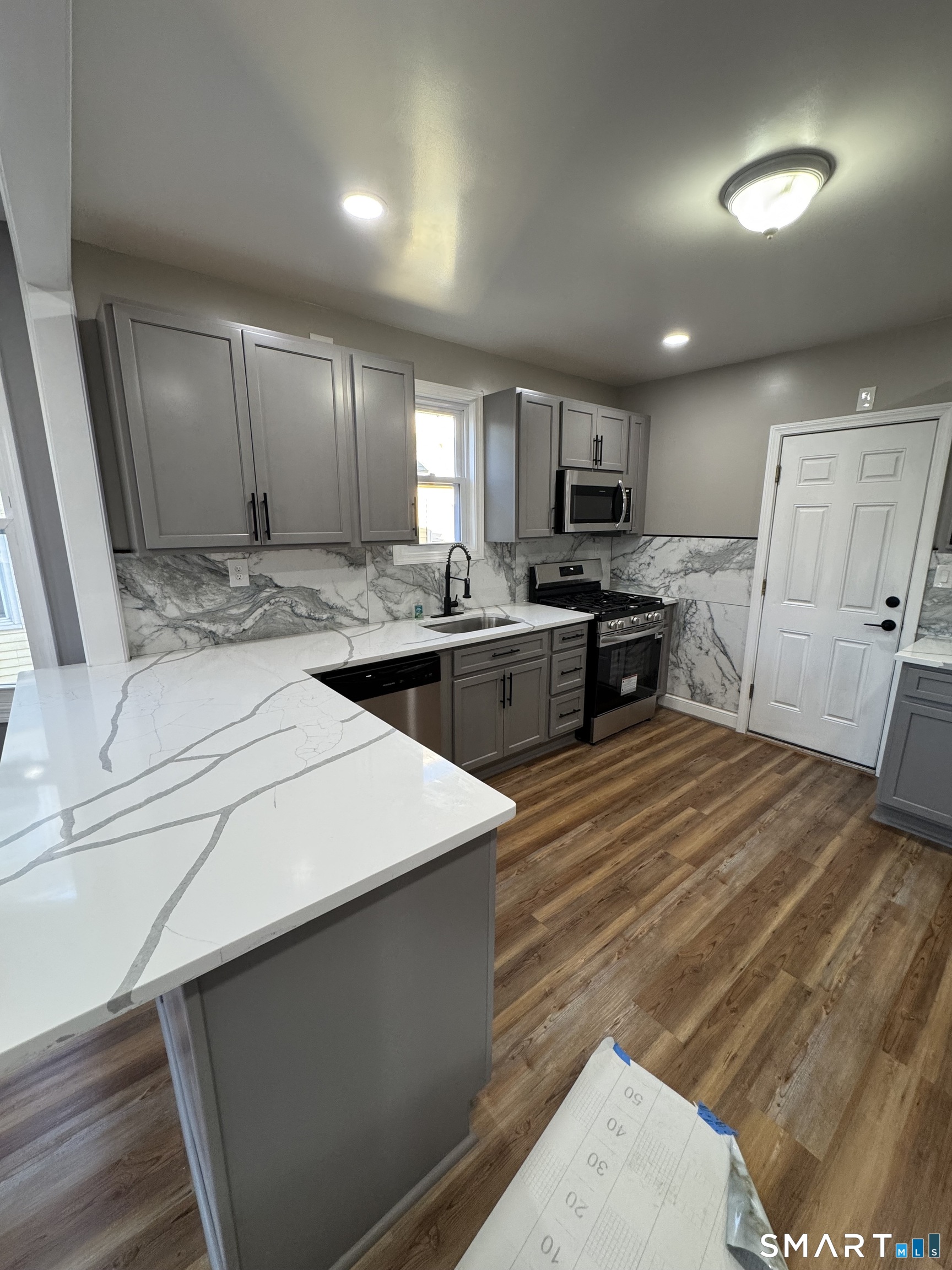 399 Hawley Avenue Bridgeport, CT 06606 - Photo 5 of 11 a large kitchen with stainless steel appliances a large counter top a stove a chimney a sink and a refrigerator