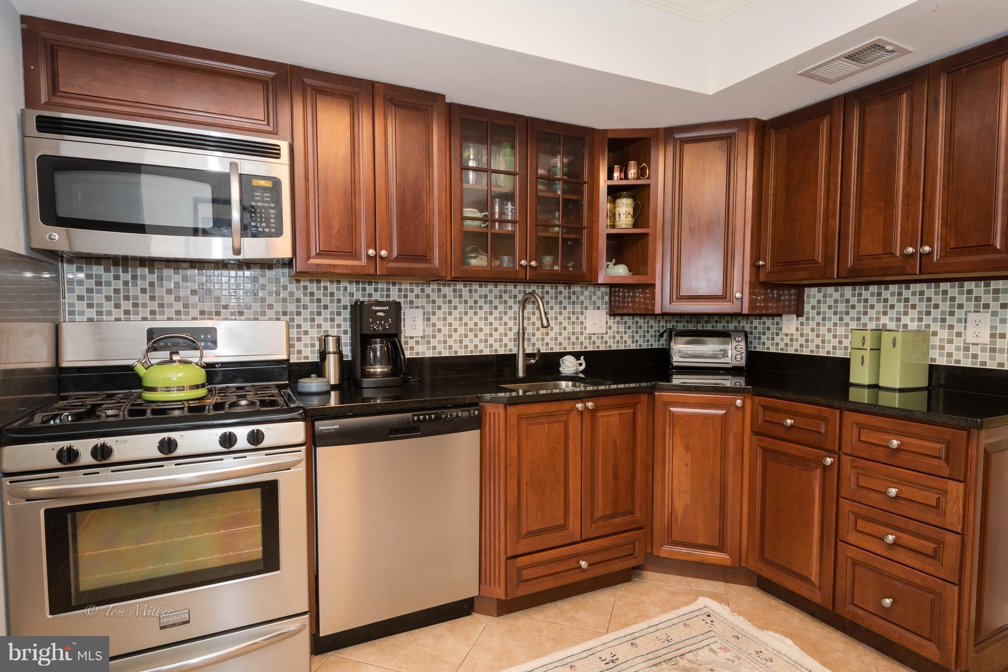 118 Cross Keys Road, Unit R118A Baltimore, MD 21210 - Photo 7 of 20 a kitchen with stainless steel appliances granite countertop wooden cabinets and a stove top oven