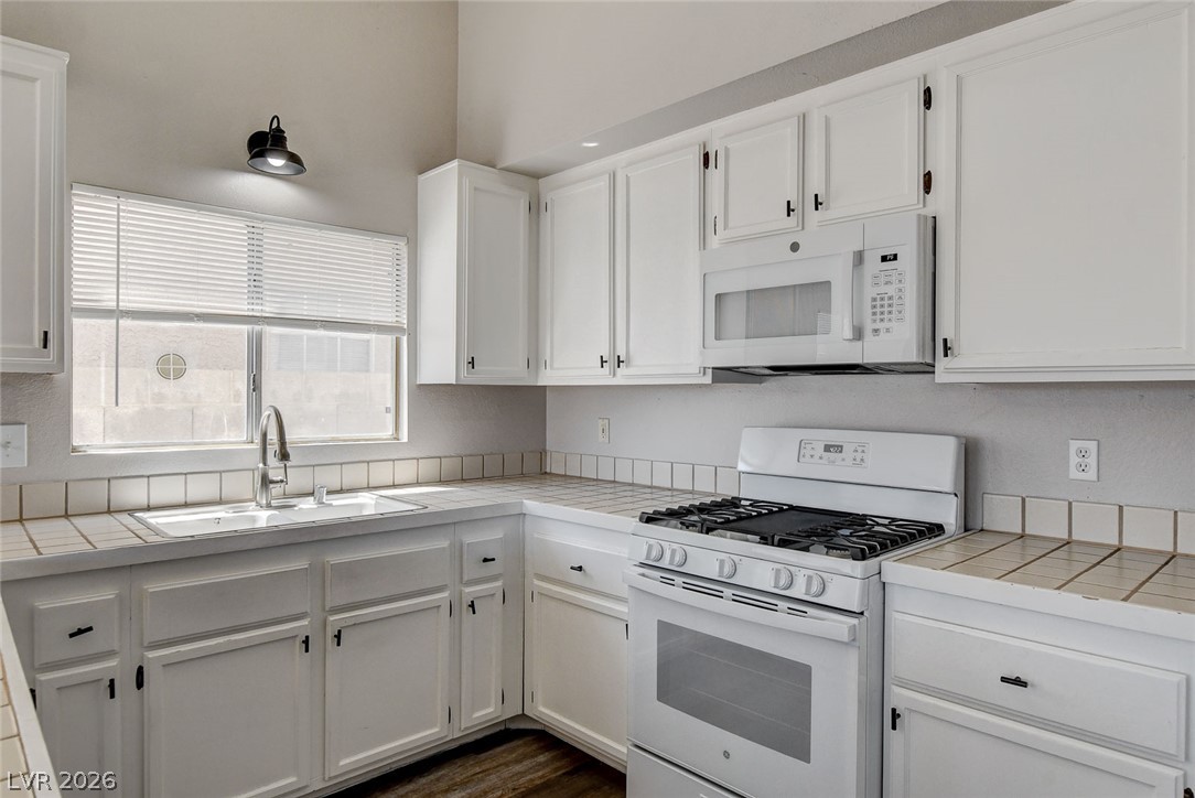 6209 Warm River Road Las Vegas, NV 89108 - Photo 17 of 39 A well-lit culinary space features bright white cabinetry and essential appliances for comfortable meal preparation.