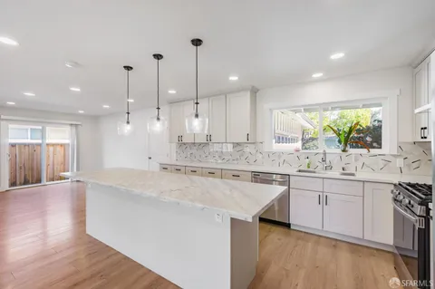 a large kitchen with stainless steel appliances granite countertop a sink a stove and a wooden floors