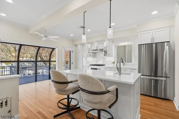 a kitchen with stainless steel appliances granite countertop a refrigerator a sink a dining table and chairs with wooden floor