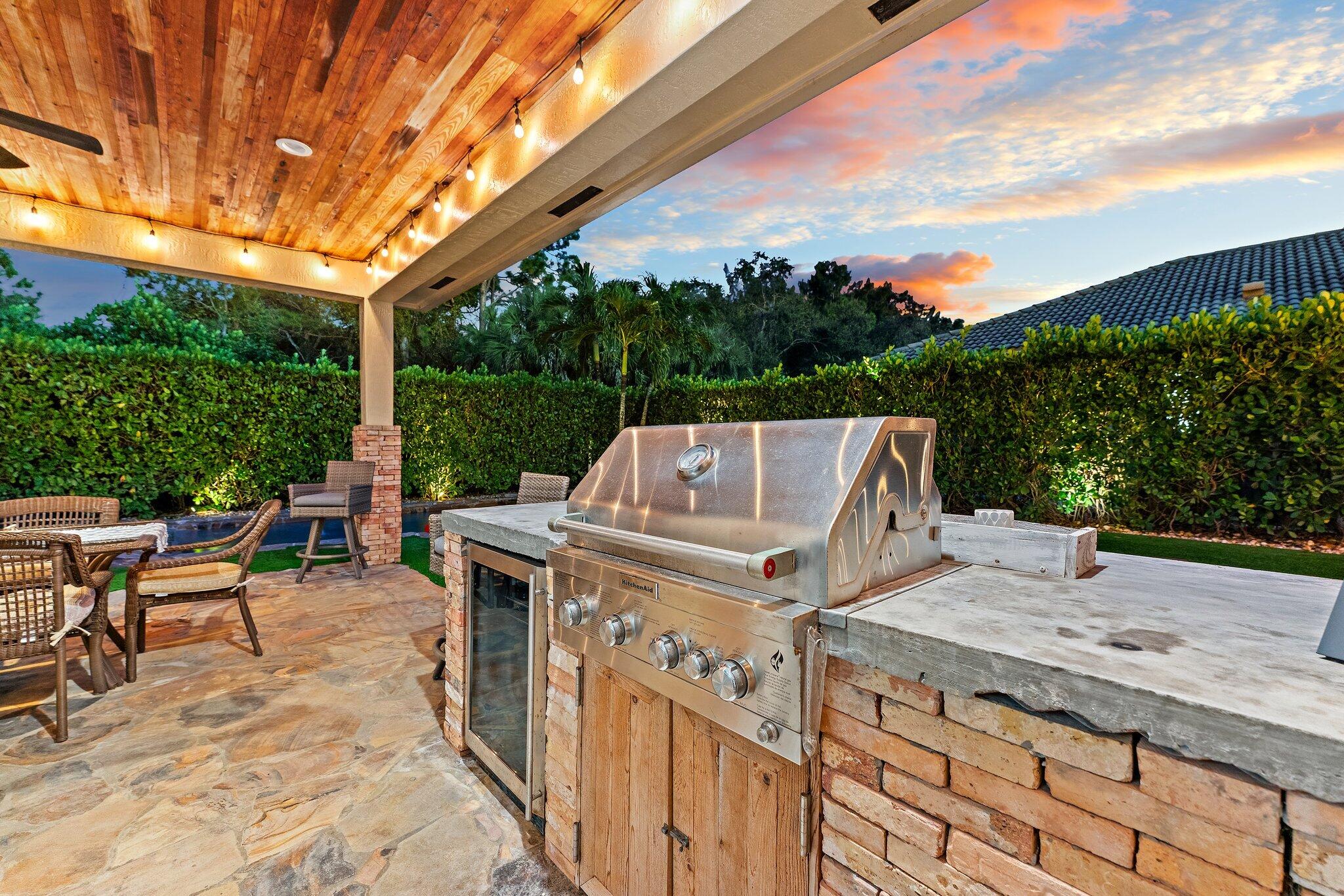 136 Via Catalunha Jupiter, FL 33458 - Photo 49 of 64 a view of a patio with table and chairs under an umbrella with a big yard