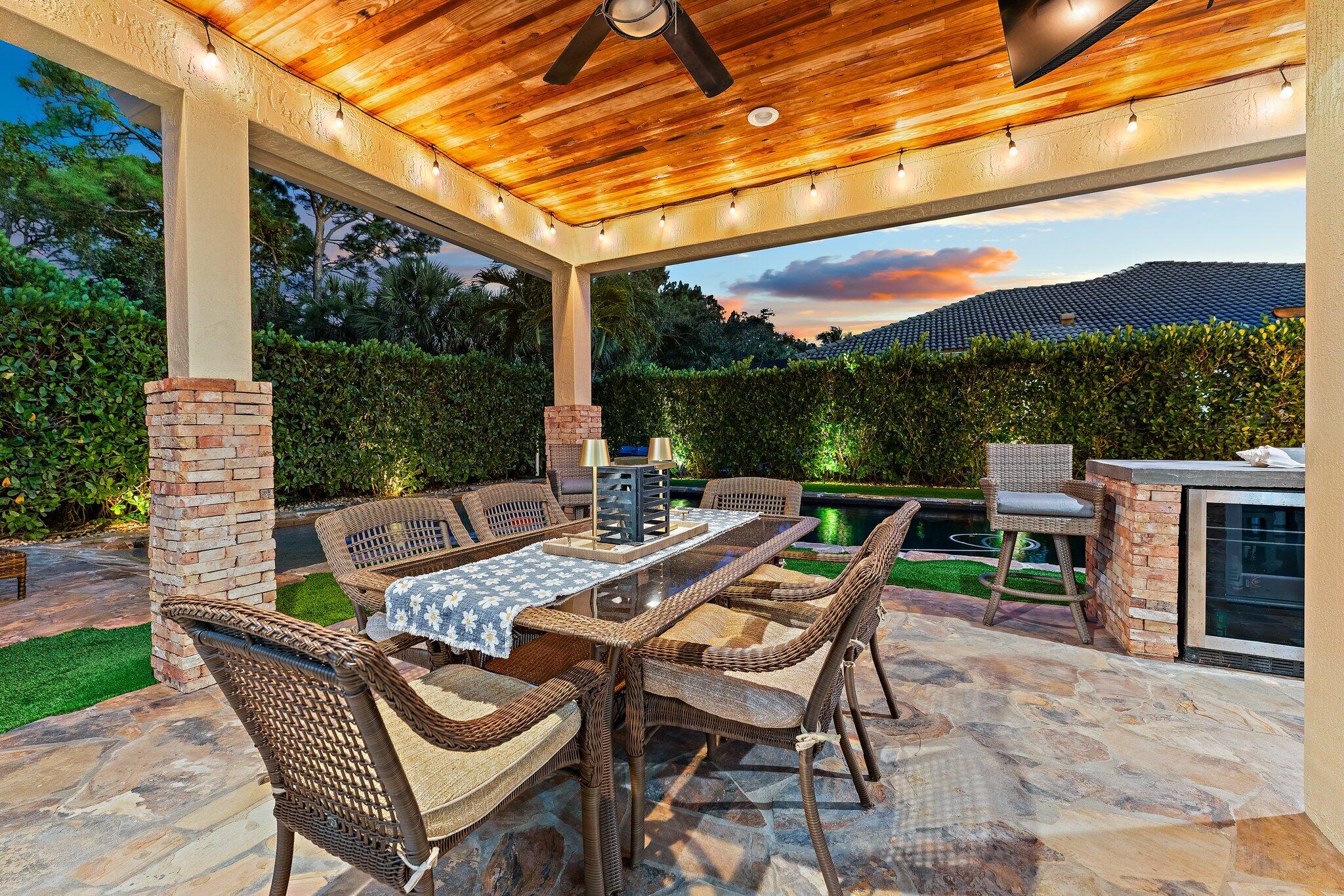 136 Via Catalunha Jupiter, FL 33458 - Photo 52 of 64 a view of a patio with a dining table and chairs with wooden floor