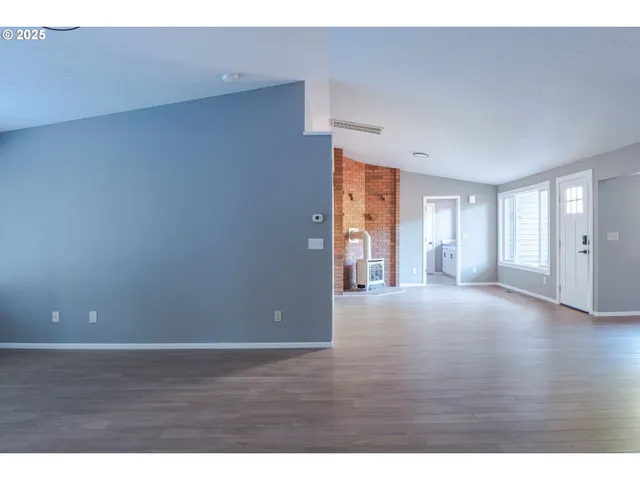 a view of an empty room with wooden floor and windows