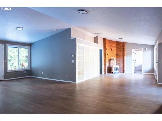 a view of an empty room with window and wooden floor