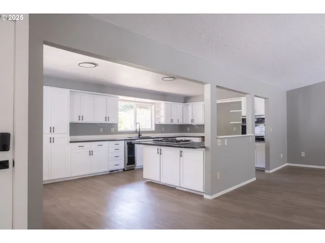 a kitchen with stainless steel appliances white cabinets and wooden floor