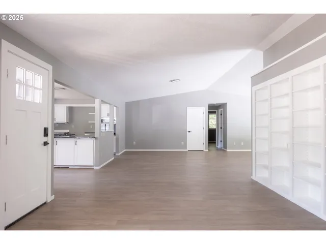a view of empty room with kitchen and window