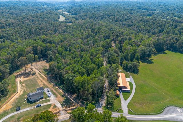 an aerial view of residential house with outdoor space and trees all around