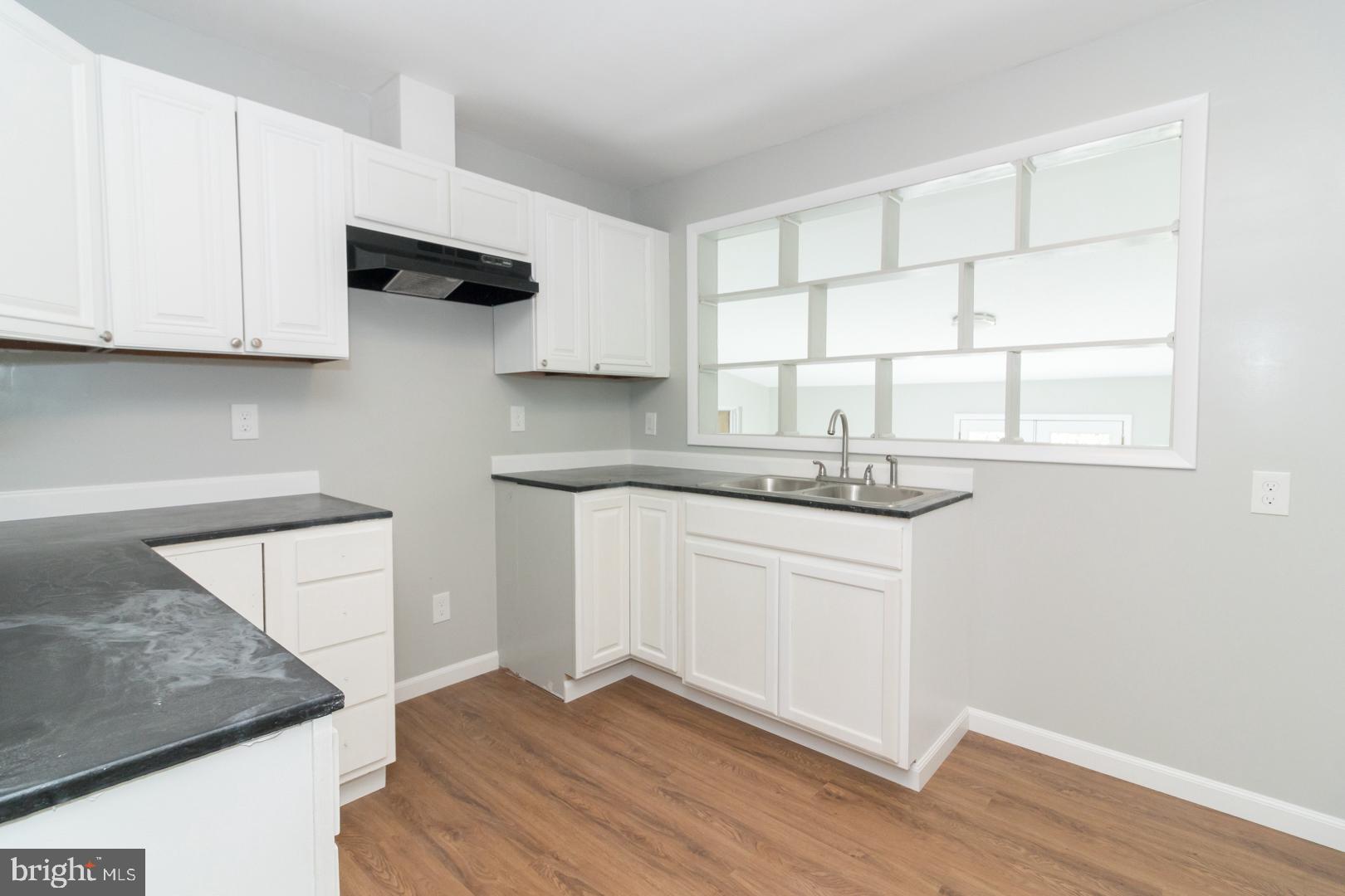 320 Fenwick Road Pilesgrove, NJ 08098 - Photo 3 of 18 a kitchen with stainless steel appliances granite countertop a sink a stove and white cabinets with wooden floor