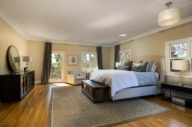 a spacious bedroom with a bed a couch and dresser with wooden floor