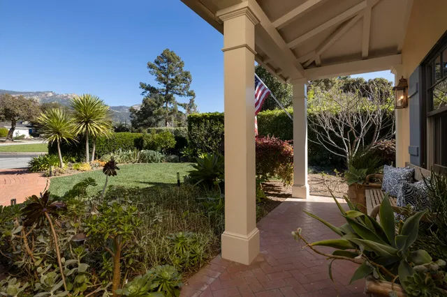 a view of a porch with potted plants and floor to ceiling window