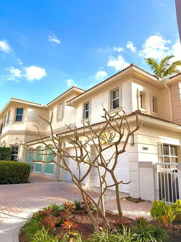 a view of a white house with a yard and potted plants