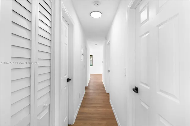 a view of a hallway with wooden floor and a shower