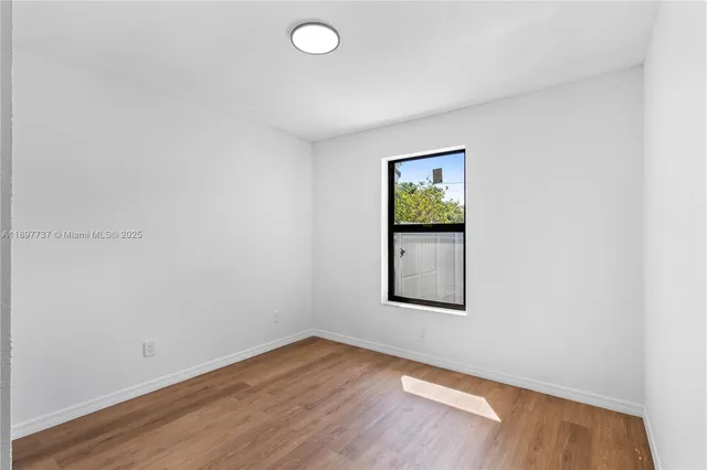 an empty room with wooden floor and window