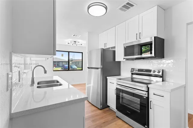 a kitchen with granite countertop a refrigerator stove and sink