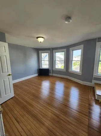 a view of an empty room with wooden floor and window
