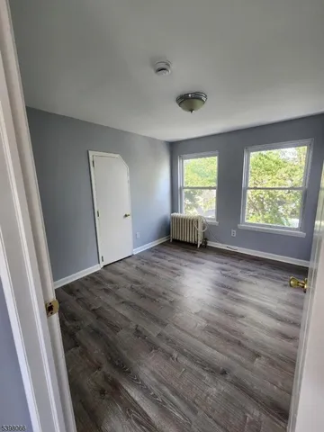 a view of empty room with window and wooden floor