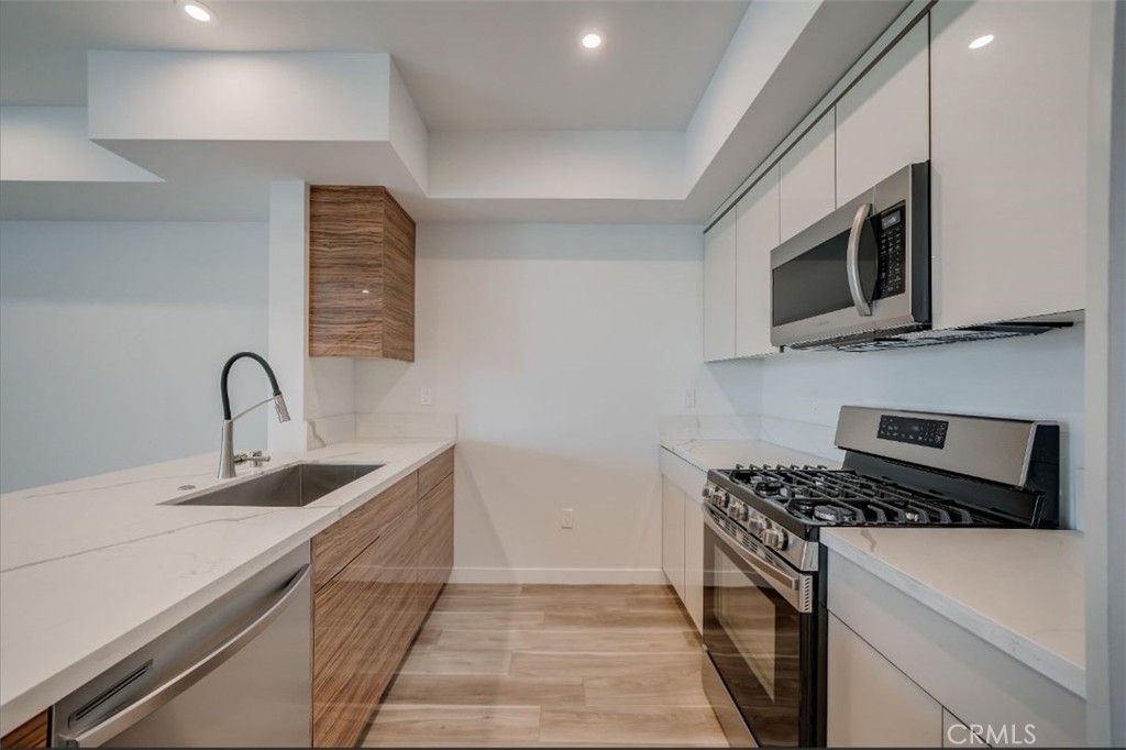 7018 Alabama Avenue, Unit 201 Canoga Park, CA 91303 - Photo 12 of 25 a kitchen with stainless steel appliances granite countertop a sink and a stove top oven