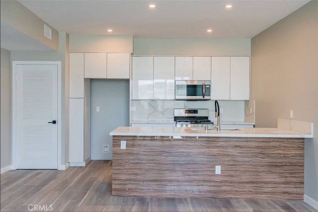 7018 Alabama Avenue, Unit 201 Canoga Park, CA 91303 - Photo 8 of 25 a kitchen with kitchen island granite countertop a stove a sink and a refrigerator
