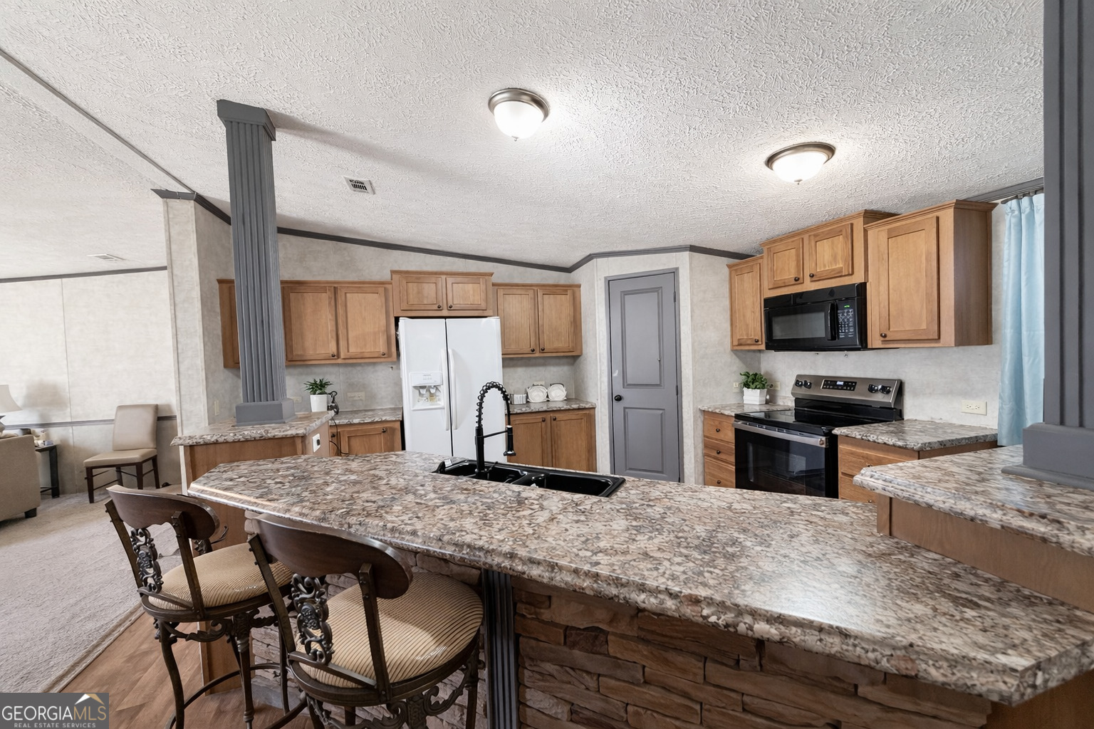195 Margarets Grove Road Crawfordville, GA 30631 - Photo 5 of 34 a kitchen with granite countertop a table chairs microwave and refrigerator